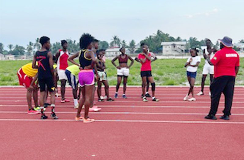 Athletics coach Johnny Gravesande at right giving final instructions to some of the District 10 (Upper Demerara / Kwakwani) at the Linden Synthetic Track on Thursday