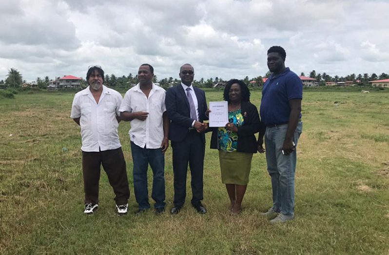 Mayor Winifred Heywood presents signed lease to president Wayne Forde on the area designated for football development, in the presence of BFA and M&TC representatives.