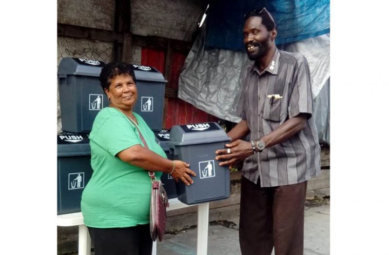 United Minibus Union (UMU) President Eon Andrews presents UG-Industry minibus operator Agnes Singh with one of the garbage receptacles.