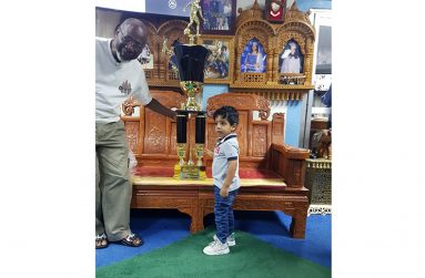 Brian Tiwari’s grandson, Bradley Gabriel, presenting the winner’s trophy to organiser Lennox Arthur for the Brian Tiwari 60th birth anniversary football tournament.
