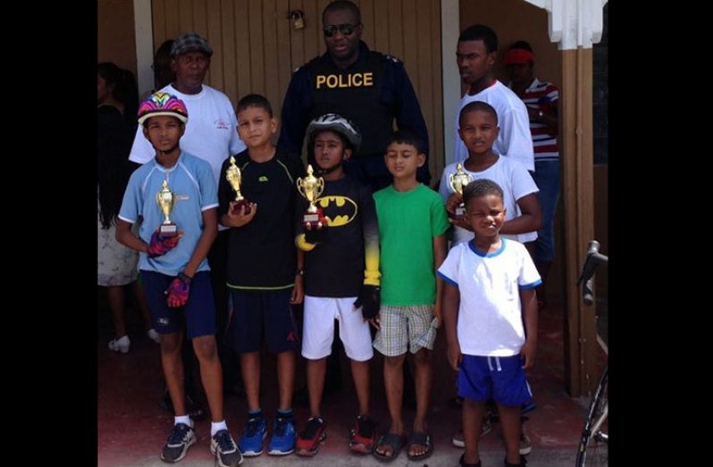 The BMX riders pose with their hardware with FACC coach Randolph Roberts. At centre is Senior Superintendent Edmond Cooper as well as winner of the 25-mile race Balram Narine.