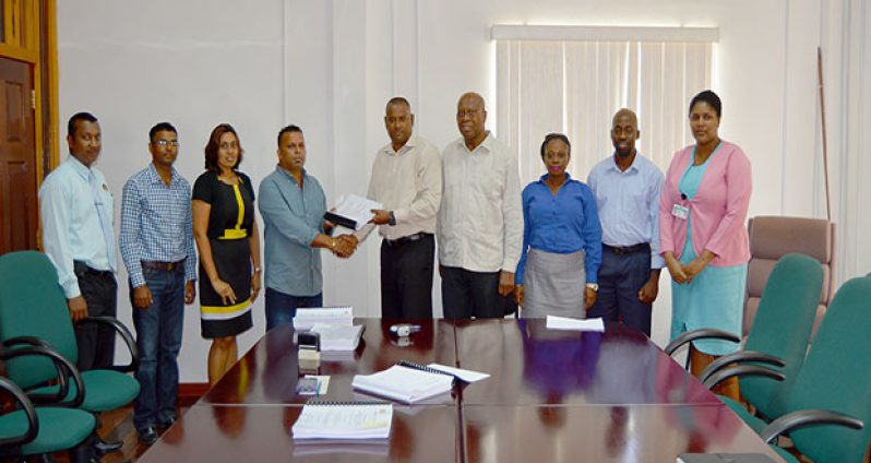 BNTF Project Manager Michael Singh hands over the contract to N Lachman – the CEO of N Lachman Business Establishment & Civil Works in the presence of Finance Secretary Dr Hector Butts and other officials