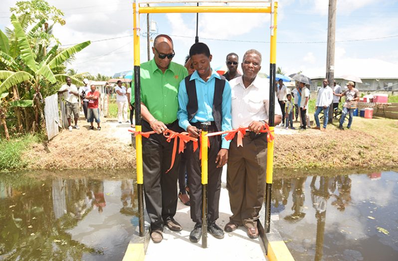 Minister of State Joseph Harmon commissions the new bridge in A’ Field, Sophia (Block ‘X’ Liliendaal) with the help of young Iziah Vilcent (Samuel Maughn photo)