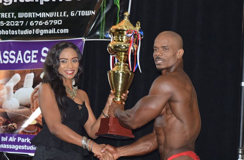 Bruce Whatley receives some of his spoils after being crowned Mr Guyana on Sunday evening.