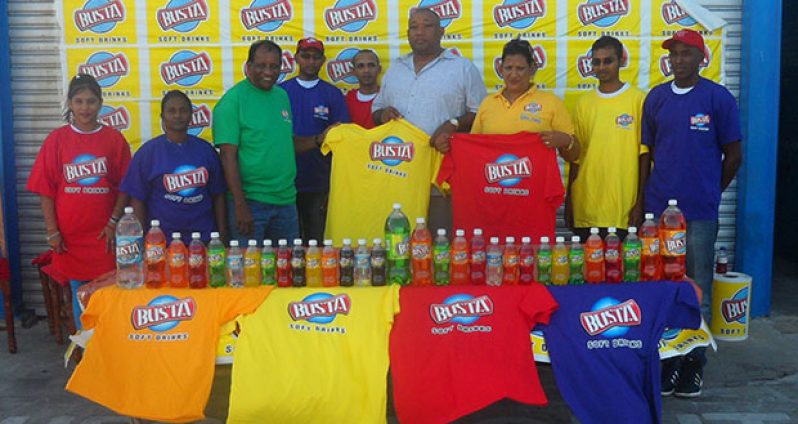 General Manager of Guyana Beverage Company Robert Selman (green top) hands over T-shirts to RHTYSC Secretary/CEO Hilbert Foster, while Marketing Manager Shameiza Yadram and other staff members proudly display others.