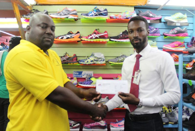 Competitions Director of the National Schools’ Championships, Ceon Bristol (left) receives the list of stationery contributed to the competition yesterday from Giftland OfficeMax Public Relations Manager, Compton Babb.