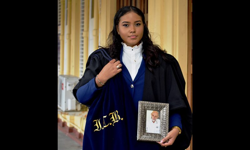 New attorney-at-law, Ismat Bacchus, holding a photograph of her late father (Carl Croker photo)