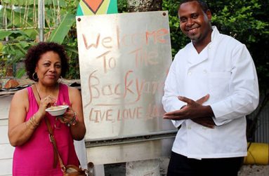 Adams (right) poses with a satisfied customer in front of the unique form of signage at the Backyard Café