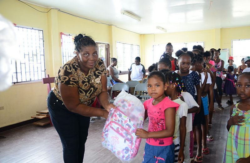 Andrea Marks presenting the haversacks to the children of Sophia and Liliendaal (Photo by Samuel Maughn)