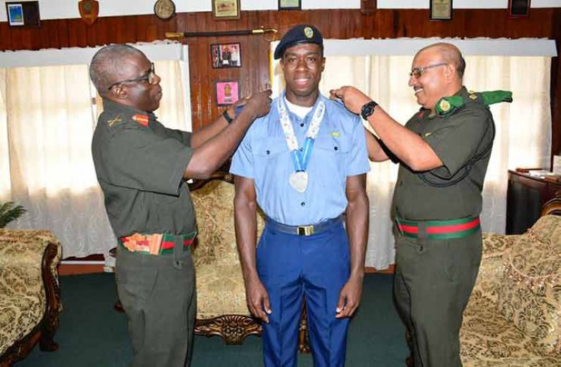 GDF’s COS Brigadier Patrick West (left) and Inspector General, Colonel Nazrul Hussain (right) decorate National Javelin record-holder and South American silver medalist, Leslain Baird with his new rank (GDF photo)