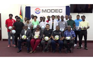 (Seated from left to right) Assistant Director of Sports, Franklyn Wilson; Jackie Boodie, Petra Secretary; MODEC Technical Manager, Joao Soares; Petra Director Troy Mendonca and Petra Representative, troy peters, flanked by players and teachers