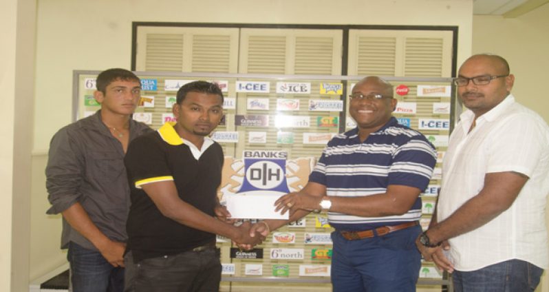 Banks DIH Limited Clive Pellew hands over the cheque to Shabeer Baksh in the presence of Gavin Jodhan and Zameer Inshan.