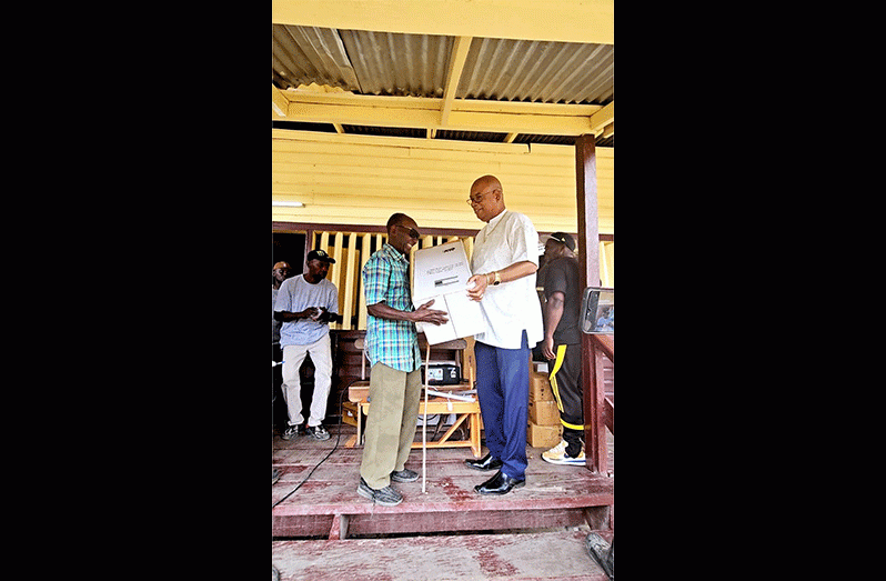 The second-eldest gentleman in the community of Baracara who is also visually impaired, Noel Amsterdam, receives his fan from Minister Edghill