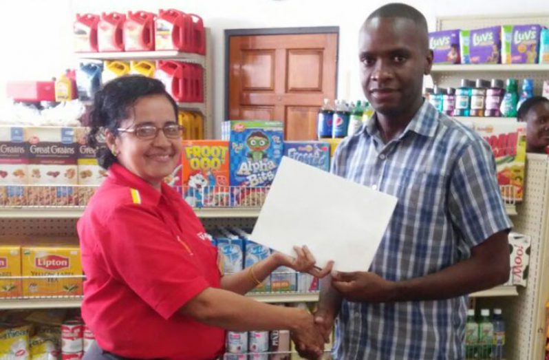 Shell Service Station Manager Patricia Callender handing over the agreement to Bartica Mayor, Gifford Marshall