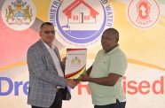 Minister of Housing and Water, Collin Croal, presents the Certificate of Title to one of the allottees at Bartica, Region Seven, Dream Realised Housing Drive Outreach