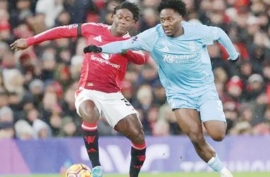 Manchester United midfielder Kobbie Mainoo and Nottingham Forest defender Ola Aina battle for possession at Old Trafford