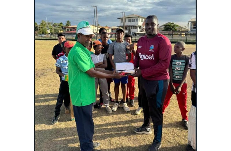 Floyd Benjamin (left) hands over the balls to Orlando Tanner in the presence of young
cricketers