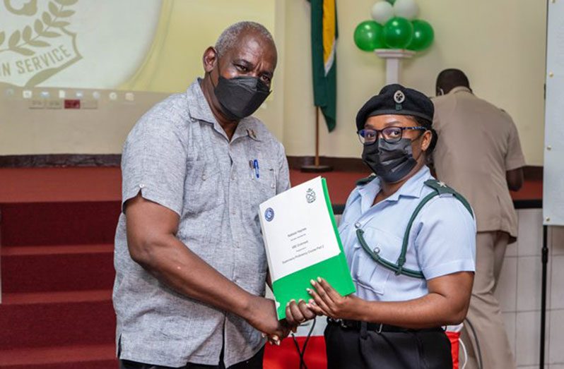 Minister of Home Affairs, Robeson Benn, handing
over certificates to a prison officer (DPI photo)