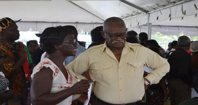 Minister of Citizenship, Winston Felix, listens keenly as a citizen airs her complaints at the outreach at New Amsterdam