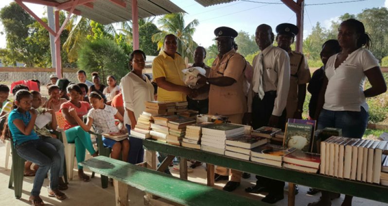 Commander Mansell of the Police ‘D’ Division handing over the books and sports gear to Director of the Best United Community Group, Antonio Paul