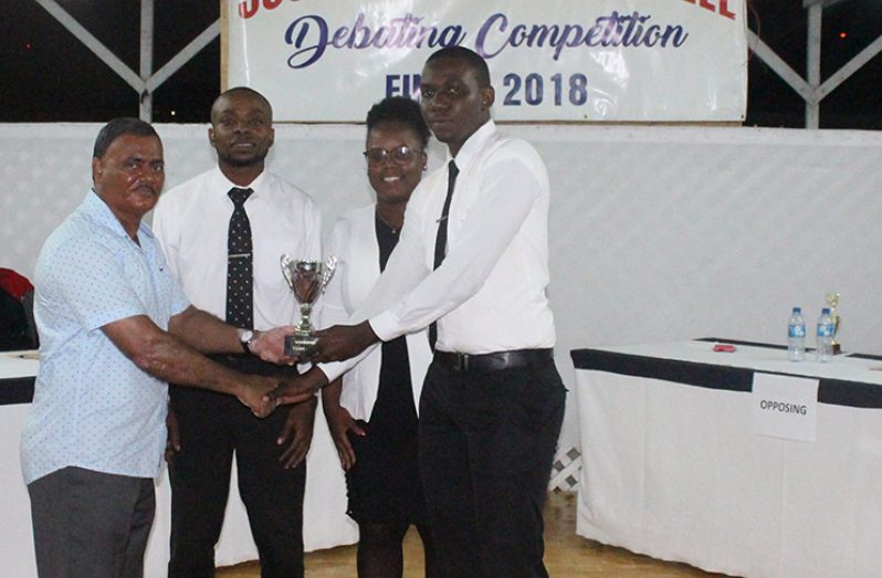 Commissioner of Police (ag) David Ramnarine presenting a trophy to Lance Corporal David Prince in the presence of the winning ‘A’ Division team members. Corporal Prince was adjudged the best speaker