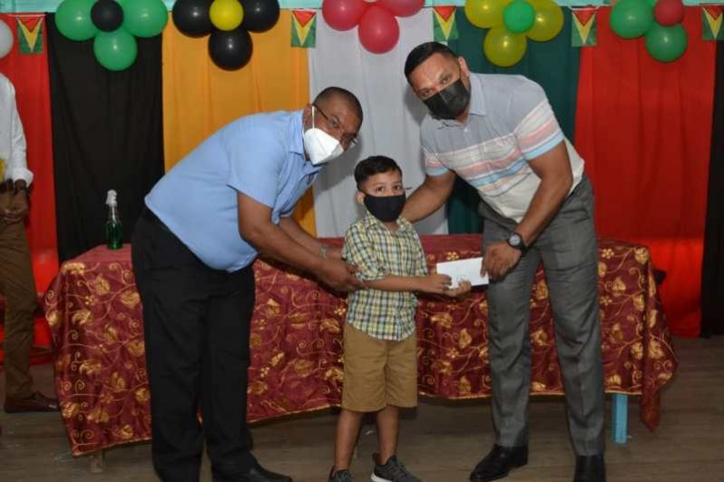 A Skeldon Line Path Nursery School pupil receives the ‘Because We Care’ grant from Natural Resources Minister, Vickram Bharrat with assistance from Region Six Regional Executive Officer, Narendra Persaud (DPI photo)