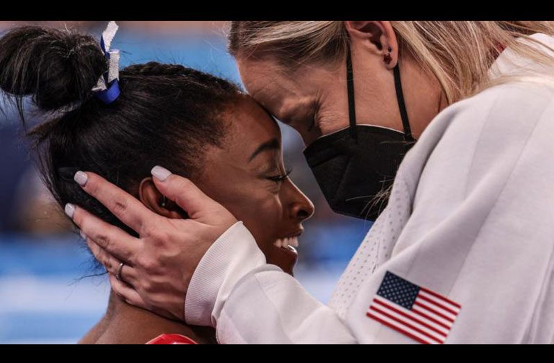 Simone Biles celebrates with her coach Cecile Landi after learning she will get a bronze medal at the women's balance beam final.