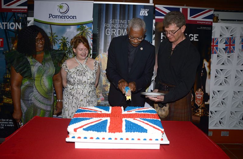 President David Granger (second right) and British High Commissioner, Greg Quinn cut the ceremonial cake to celebrate Queen Elizabeth II’s birthday. Looking on at left and second left are: Minister of Foreign Affairs, Dr. Karen Cummings, and Mrs Wendy Quinn, wife of the British High Commissioner (Adrian Narine photo)
