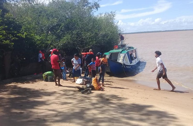 The passengers stand ashore along the Essequibo River after the boat’s captain was forced to beach the vessel following the incident.