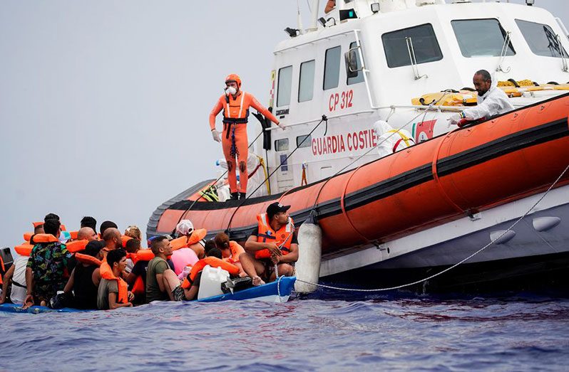 Members of Italian Guardia Costiera prepare to bring on board the migrants of a wooden boat near the island of Lampedusa, in the Mediterranean Sea, September 1, 2021 (REUTERS/Juan Medina)