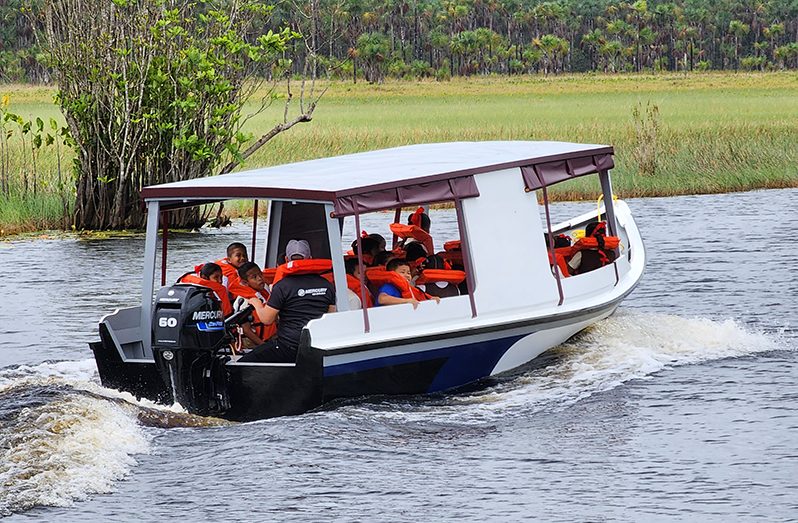 Schoolchildren of Akawini Village, Region Two, using the 25-foot wooden boat, with a 60HP four-stroke Mercury outboard engine