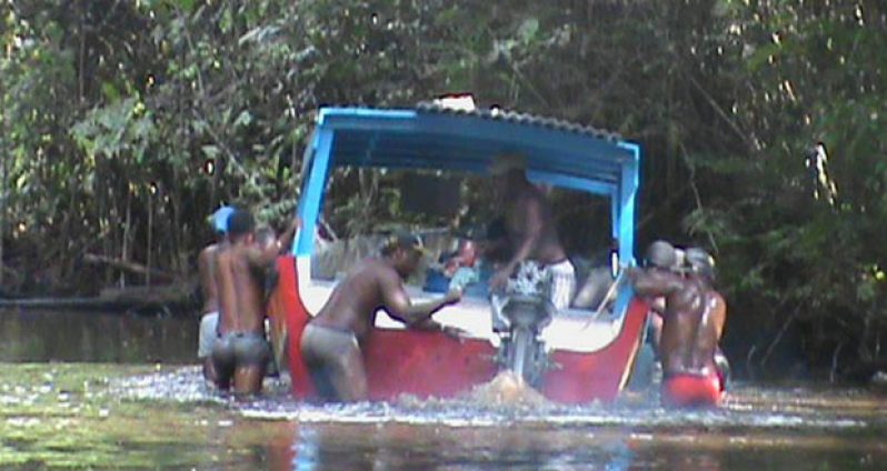 Low water level in the areas of Dark Bush and 99 Turns has caused miners serious problems. In picture, a group of miners struggle to get their boat across to deeper water.