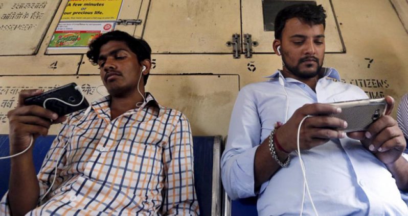Commuters watch videos on their mobile phones as they travel in a suburban train in Mumbai, India, April 2, 2016. (REUTERS/Shailesh Andrade)