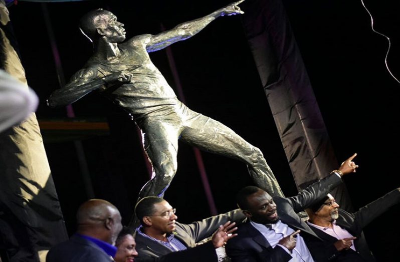 Jamaican sprint legend Usain Bolt (second right) does his trademark ‘to the world’ pose in front of a statue of his likeness at the National Stadium in Kingston on Sunday. He's joined by (from left) his coach Glen Mills, Sport Minister Olivia Grange, and Prime Minister Andrew Holness. (PHOTOS: Marlon Reid)