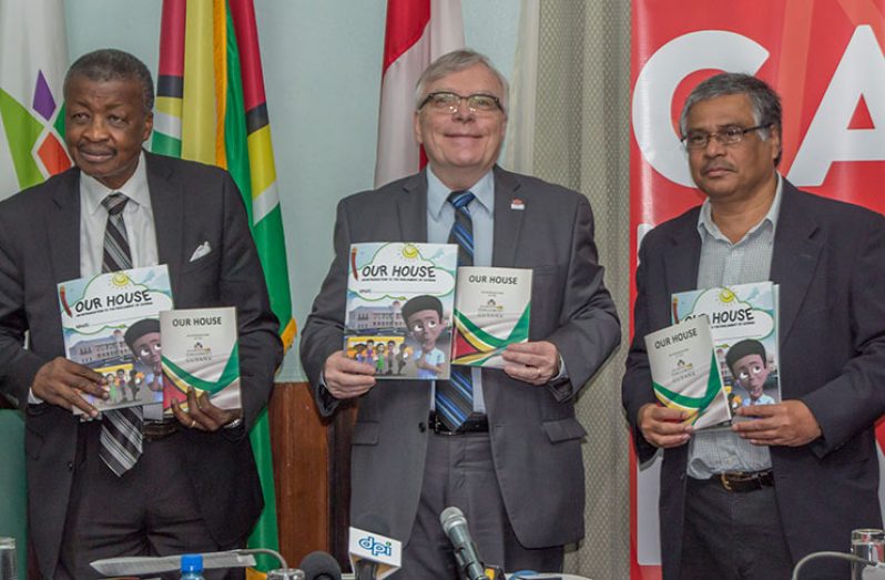 Speaker of the National Assembly, Dr. Barton Scotland; Canadian High Commissioner, Pierre Giroux and President of the Association of Caribbean Media Workers, Wesley Gibbings pose with their adult and child-friendly copies of ‘Our House’ [Adrian Persaud photo]