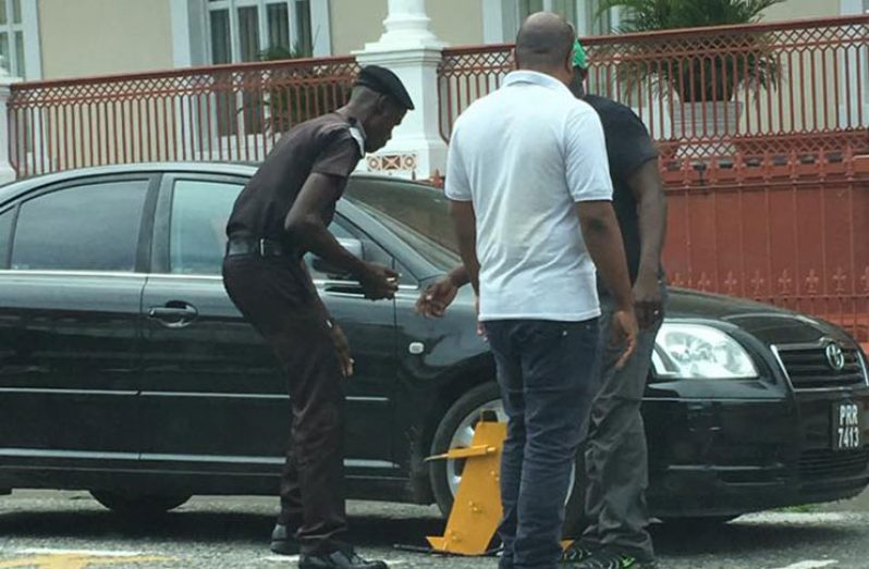 A City Constabulary office and a staff of Smart City Solutions demonstrates how a vehicle will be wheel-booted if the driver fails to pay for a demarcated spot which he/she is required to pay for