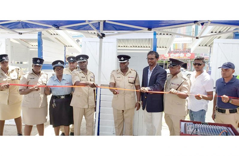 Commander Edmond Cooper cutting the ceremonial ribbon with Deputy Commander Dion Moore (left), President of the Region Three Chamber of Commerce, Halim Khan (right), flanked by other law enforcement officers