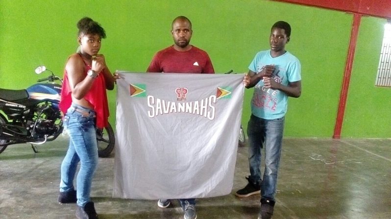 Members of the Savanah Boxing Gym pose with the gym flag at the National Gynasium yesterday. Boxers Julicia Rodney (left) and Troy Nero. Coach Floyd Vincent is at centre.