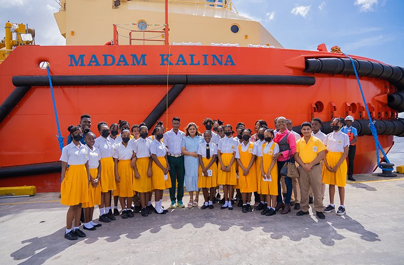 Minister of Education, Priya Manickchand with students of the Brickdam Secondary School including Kaylan Duncan and Raymond De Cambra of the St. Ignatius Secondary School in front of the Madam Kalina which was named by Kaylan