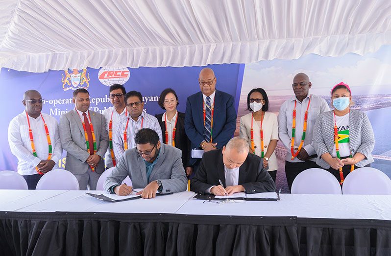 Permanent Secretary of the Ministry of Public Works, Vladim Persaud (seated at left), and a representative of the China Railway Construction Corporation sign the contract for the project, in the presence of Cabinet members and other officials. (Delano Williams photos) 