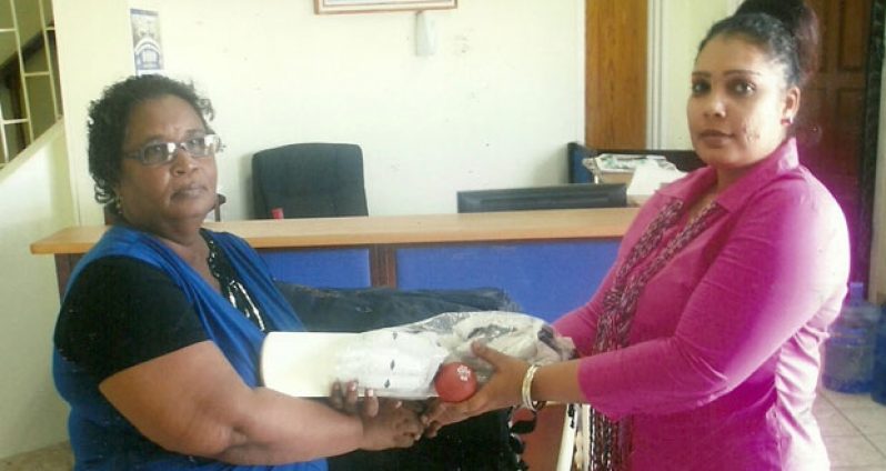 Administrative Assistant of Berbice Bridge Company Bibi Alli (right) hands over  one of the coaching kits to Secretary of the Berbice Cricket Board, Angela Haniff.