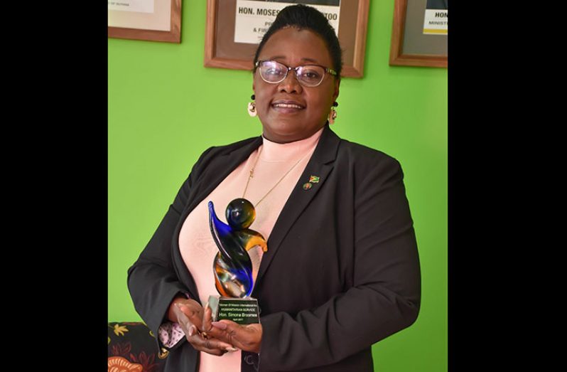 Minister within the Ministry of Natural
Resources Simona Broomes holds a
trophy she received from Women of
Mission International for humanitarian
service. (Kawise Wishart photo)