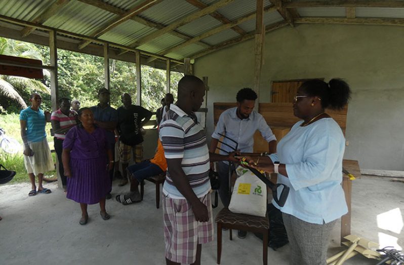 Minister within the Ministry of Natural Resources, Simona Broomes presenting farmers in West Watooka with farming tools
