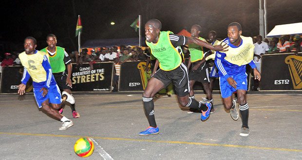 North Ruimveldt’s Joshua Browne (centre green bib), goes after the ball during his side’s quarterfinal matchup against Hope Street-Tiger Bay last Wednesday night at the National Cultural Centre tarmac. (Photo by Sonell Nelson)