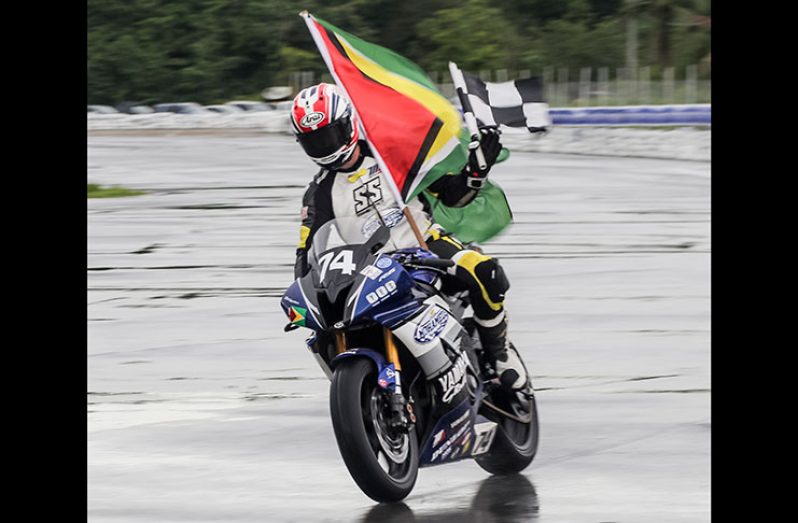 Bryce Prince displays the Guyana flag and the chequered flag yesterday at the Frankie Boodhram International Raceway. (David Persad/ TriniTuner.com)