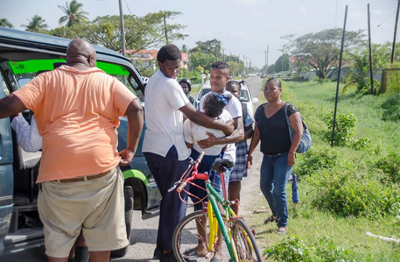 The injured teenager of the Lusignan Secondary School being taken into a minibus by public spirited citizens after she was stabbed in the neck (Adrian Persaud photo)