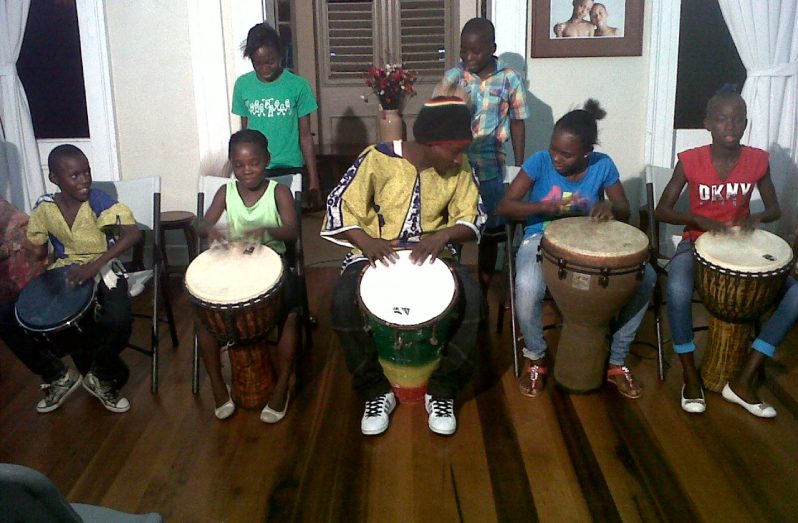 Marlon ‘Chucky’ Adams (centre) teaching young children how to drum