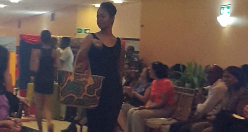 A CARICOM staffer struts the runway showcasing a Veroké handbag