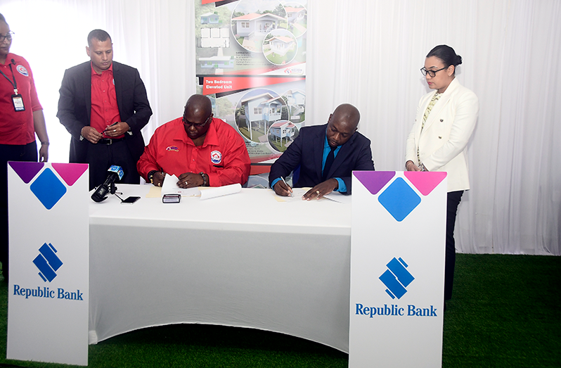 Housing Minister Collin Croal (left) and Minister within the Ministry of Housing Susan Rodrigues (Right) overlooking the Signing of the MOU being carried out by CH&PA’s Chief Executive Officer, Sherwyn Greaves, (seated left) and Republic Bank’s General Manager (Credit), Venus Frith, at the International Building Expo at the Guyana National Stadium, Providence  (Adrian Narine photo)