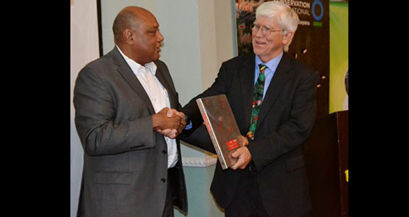 Minister of Natural Resources, Raphael Trotman, presenting a token of appreciation to Conservation International President Dr Russell Mittermeier on Monday evening